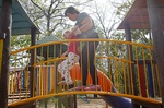 A mãe Bianca Lopes ajuda sua filha Sofia a subir nos brinquedos do parque